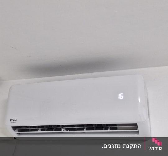 מזגן מותקן על קיר לבן עם צינור חיבור